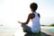 Young woman sitting at beach in yoga pose