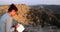 Young woman sitting on bench above hills writing in notebook in Vashlovani national park in Georgia