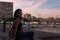 Young woman is sitting on a bench in a harbor