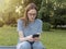 Young woman sitting on bench and using phone. Serious anxious person looking on smartphone in nature