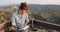 Young woman sitting on bench writing in notebook at Vashlovani national park in Georgia