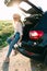 Young woman sitting in the car trunk on the roadside in the forest