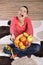 Young woman sitting on carpet and enjoying fruits