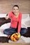 Young woman sitting on carpet and enjoying fruits