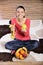 Young woman sitting on carpet and enjoying fruits