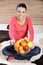 Young woman sitting on carpet and enjoying fruits