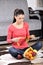 Young woman sitting on carpet and enjoying fruits