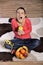 Young woman sitting on carpet and enjoying fruits