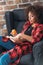 Young woman sitting in chair and studying with books while eating apple