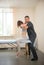 Young woman sitting on the couch and having osteopathic treatment in the clinic - holding her neck with both hands - the