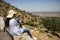 Young woman sitting on the edge of the cliff enjoying Beni Melal-Jenifra which is located between the Middle Atlas and the Tadla