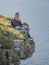 Young woman sitting on the edge of a cliff at the Irish west coast