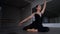 Young woman sitting on floor performing ballet movements lying down. Portrait of skilled Caucasian ballerina rehearsing