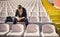 A young woman is sitting on the grandstand and taking a rest after a training at the stadium. Sport, athletics, athletes