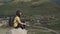 Young woman sitting on hill. Dreamy female sitting on altitude and looking at Peaks of magnificent rocks located against