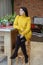 A young woman is sitting in the kitchen in a yellow knitted sweater. Concept home, comfort, lifestyle, autumn, winter