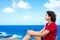 Young woman sitting on large rock cliff by Hawaiian ocean