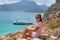 Young woman sitting on a large rock and looks into the distance at sea. Selective soft focus. Balos Lagoon