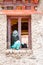 Young woman sitting in a monastery windows span watching a religious festival