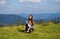 Young woman sitting on mountain top peacefully gazing at low-lying morning clouds