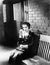 Young woman sitting n a bench in front of a jail cell