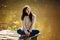 Young woman sitting on the old bridge barefoot. Summer, green forest, lake and air in the evening bring the mood to relax,