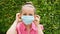 Young woman sitting outdoor and putting on a surgical protective mask against viruses during coronavirus COVID-19 epidemic danger