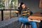 Young woman sitting outdoors at comfortable cafeteria while waiting friends. Happy young woman sitting outdoors in the coffee shop