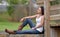 Young woman sitting outside in white tank and denim