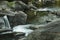 Young woman sitting in rapids of Sugar River, Newport, New Hampshire.