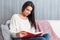 Young woman sitting read book couch sofa at home