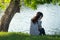 Young woman sitting on river bank under tree on head her wear he