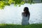 Young woman sitting on river bank under tree on head her wear he