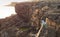 Young woman sitting on rock ledge and looking at ocean bay