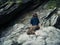 Young woman sitting on rock outside cave