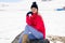 Young woman sitting on a rock in the snowy mountains in winter, in Sierra Nevada, Granada, Spain.