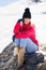 Young woman sitting on a rock in the snowy mountains in winter, in Sierra Nevada, Granada, Spain.