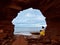 Young woman sitting on rocks under the sea cliffs at Cavendish Beach, Prince Edward Island, Canada