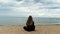 Young woman sitting on sea shore and looking into the distance. Concept. Rear view of young girl with long curly