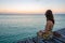 Young woman sitting on seaside jetty at sunset