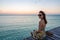 Young woman sitting on seaside jetty at sunset