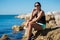 Young woman sitting on seaside rock thinking