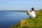 Young woman sitting on the shore of the lake with blank sheet of