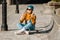 Young woman sitting on skateboard, using phone. skateboarding woman in city. female skate boarder with smartphone and skateboard.