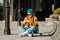 Young woman sitting on skateboard, using phone. skateboarding woman in city. female skate boarder with smartphone and skateboard.