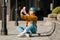 Young woman sitting on skateboard, using phone. skateboarding woman in city. female skate boarder with smartphone and skateboard.