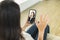 Young woman sitting on sofa at home, holding mobile phone, making video call, discussing with company colleagues in telecommuting