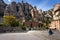 Young woman is sitting on steps among buildings of Montserrat monastery located between huge rocks in Catalonia, Spain