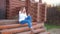 Young Woman Sitting On The Steps Of The Porch Of Wooden House And Drinking Tea