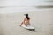 young woman sitting on surfboard on tropical